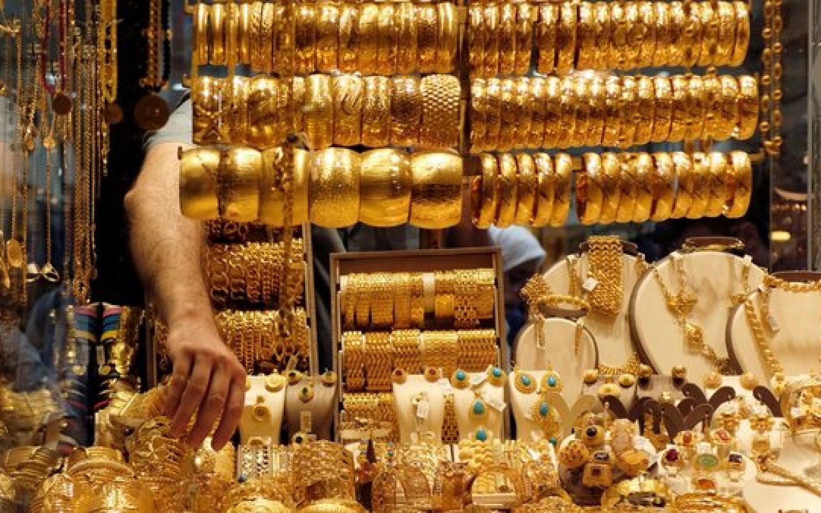 أوضح نادي نجيب سكرتير عام شعبة الذهب بغرفة القاهرة التجارية سابقا، إن تجار الذهب يترقبون أداء السوق المحلي مطلع الأسبوع المقبل، مع عودة العمل في البنوك بعد إجازة عيد الفطر. وأضاف نجيب أن ارتفاع سعر الذهب العالمي اليوم، ليس محفزا كبيرا لزيادة سعر الجرام في السوق المحلي، لأن سعر الأوقية لم يصل حتى لمستوى 1900 أو 2000 دولار للأوقية التي سبق ووصل لها. "الدولار هو السبب الرئيسي في أي زيادة مستقبلية في سعر الذهب في السوق المحلي، خاصة وأن هناك زيادة في الطلب على الذهب من المستثمرين في مصر كملاذ آمن" وفقا لنادي. وأشار نجيب إلى أنه في حال ارتفع سعر الدولار في مصر خلال الفترة المقبلة "قد نرى زيادة في سعر الذهب نتيجة لهذا". وأوضح أن زيادة الأسعار ولجوء المستثمرين للذهب، رفع الطلب على الذهب في مصر ما بين 10-15% خلال الفترة الماضية على الرغم من طرح البنوك الشهادة الاستثمارية بعائد 18%. ولا يتوقع نادي نجيب أن يؤثر أي تحرك محتمل للدولار على توافر المعروض من الذهب مضيفاً "لدينا كميات ذهب كبيرة ونصدر جزء من الفائض لذلك لا يتوقع أن تعاني مصر من أزمة في المعروض منه في السوق". وتوقع ناجي فرج، رئيس اللجنة الاقتصادية بشعبة الذهب بغرفة القاهرة التجارية، تحركا متوازنا لسعر الذهب في مصر خلال الفترة المقبلة وفقا للمعطيات الحالية. وقال إنه من المتوقع أن يتداول في المتوسط ما بين 1130إلى 1150 جنيه للجرام من الذهب عيار 21. "الذهب وصل إلى سعر ليس بسيطا، ولا يمكن استباق تأثير رفع الفائدة على سعر الدولار وبالتالي لا يمكن بناء فرضية على أساس تحرك الدولار" وفقا لفرج.