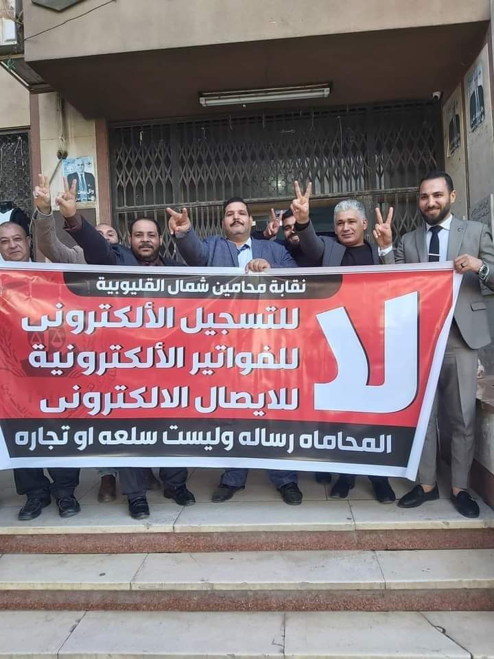 تواصل نقابة محامين شمال القليوبية، مشاركاتها مع القاهرة والمحافظات الاخرى، في وقفات الاحتجاج على إلزامهم بالتسجيل في الفاتورة الإلكترونية، مؤكدة في بيان لها أنها تستشعر الخطر فيما يجرى من محاولة فرض الفاتورة الإلكترونية على المحامين. وأكدت النقابة على رفضها التام لتسجيل المحامين في منظومة الفاتورة الإلكترونية لأن المحاماة مهنة لا تتعلق بتداول السلع أو الاتجار فيها وأن أعمالها هي أعمال قانونية وذهنية. وأصدرت نقابة المحامين بشمال القليوبية بيان لها، عن الاعتراض على منظومة الفاتورة الالكترونية، مؤكدين المشاركة في الوقفة. وجاء في البيان: "نقابة محامين شمال القليوبية:- أولاً - المشاركة في الوقفة السلمية المحددة لها النقابة العامة للقاهرة تضامنا مع باقي النقابات الفرعية وتوفير وسيلة الانتقال الي النقابة العامة من النقابات الفرعية. ثانياً - تقرر وقف التعامل مع جميع خزن محاكم شمال القليوبية يومي 7 و 8/ 2022/12. ثالثاً - الدعوة الي اجتماع جمعية عمومية طارئ السبت المقبل الموافق 10/12/2022, وذلك لمناقشة أخر المستجدات وفقاً لأخر الأوضاع. رابعاً - من يخالف قرار المجلس يحال للتأديب. خامساً - تم إحالة جميع من يخالف القرار الي النقابة العامة. كانت ودعت مصلحة الضرائب مؤخرًا جميع الممولين ومنهم أصحاب المهن الحرة ممن لديهم تعاملات مع المستهلكين النهائيين إلى التسجيل بمنظومة الفاتورة الإلكترونية في موعد أقصاه 15 ديسمبر الجاري. وقال مجدي المهدي نقيب المحامين بشمال القليوبية، المحامون لا يحملون الدولة أية أعباء مالية بل أن المحامين لا تحصل على أي حق من الحقوق كأي مواطن اخر، مؤكدا أنهم لا يحصلون على معاشات من الدولة بل أن دخلهم من عملهم القانوني المباشر فقط. واضاف "المهدي" لن تتردد النقابة في اتخاذ أية إجراءات تكفل منع تطبيق الفاتورة الإلكترونية على المحامين والدفاع عن حقوق أعضاء النقابة. وأكد أحمد رمضان محام وعضو اللجنة النقابية بشمال القليوبية، أن النقابة لا تزال في حالة انعقاد دائم لحين انتهاء الأزمة بالعدول عن قرار تسجيل المحامين بمنظومة الفاتورة الإلكترونية"، مضيفا ان هناك تصعيد في حالة استمرار فشل مفاوضات لجنة المشكلة بين وزارة المالية والنقابة العامة لحل الأزمة. وطالب أحمد رمضان علي بضرورة الغاء قرار تسجيل المحامين بمنظومة الفاتورة الإلكترونية لكون المحاماه رسالة وليست مهنة تجارية. كانت قررت الجمعية العمومية لمحامي مصر اليوم الخامس من ديسمبر ٢٠٢٢م الآتي : ١- الإمتناع التام عن التعامل مع الخزينة بالمحكمة وسداد أية رسوم على مستوى كل محاكم مصر بكل الجزئيات، ويستثنى من ذلك الدعاوى والإجراءات المرتبطة بمواعيد، وكلفت مجالس النقابات الفرعية بتنفيذ ذلك. ٢- حددت موعد الخميس الموافق ٨ ديسمبر ٢٠٢٢م الساعة ١٢ ظهرًا بالنقابة العامة للمحامين لعرض قرار الإضراب عن العمل. ٣- أكدت الجمعية العمومية للمحامين مصر على النقيب العام ومجلسه بضرورة الالتزام بتنفيذ قرارات الجمعية العمومية. ٤- نبهت الجمعية العمومية للمحامين مصلحة الضرائب المصريه بسرعة العدول عن القرار الباطل بإلزام السادة المحامين بالإشتراك بمنظومة الفاتورة الإلكترونية والإيصال الإلكتروني. ٥- نبهت الجمعية العمومية للمحامين على المستشار وزير العدل بأنه لا رسوم إلا بقانون، وأنه عليه وقف قرارات رؤساء بعض المحاكم بفرض رسوم جديدة بناء على تعليمات وبالمخالفة لقانون الرسوم القضائية. ٦- طالبت الجمعية العمومية للمحامين من البرلمان المصري التصدي للمحاولات الباطلة بإخضاع السادة المحامين لمنظومة الفاتورة الإلكترونية والإيصال الإلكتروني. وتوجه شكر للسادة النواب الذين تقدموا بطالبات إحاطة للبرلمان . ٧- طالبت الجمعية العمومية للمحامين من المحكمة الدستورية العليا الفصل في الطعن الدستوري بشأن قانون القيمه المضافة وبطلان إلزام المحامي بضريبة الجدول. وأكدت على الموعد الخميس ٨ ديسمبر ٢٠٢٢م